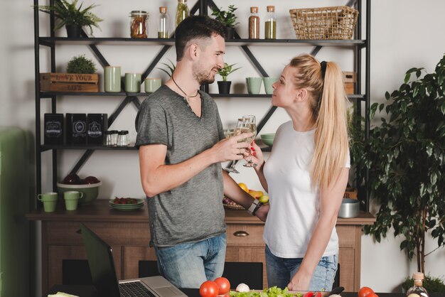 Młoda para wznosi toast szampańską fletową pozycję w kuchni