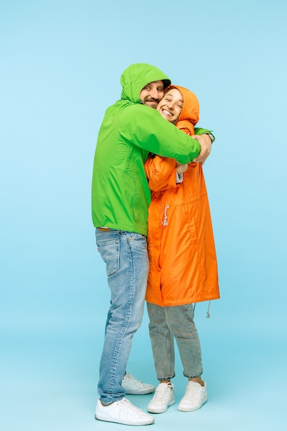 Bezpłatne zdjęcie młoda para zaskoczony w studio w jesienne kurtki odizolowane na niebiesko. ludzkie szczęśliwe pozytywne emocje. pojęcie zimnej pogody. koncepcje mody męskiej i żeńskiej