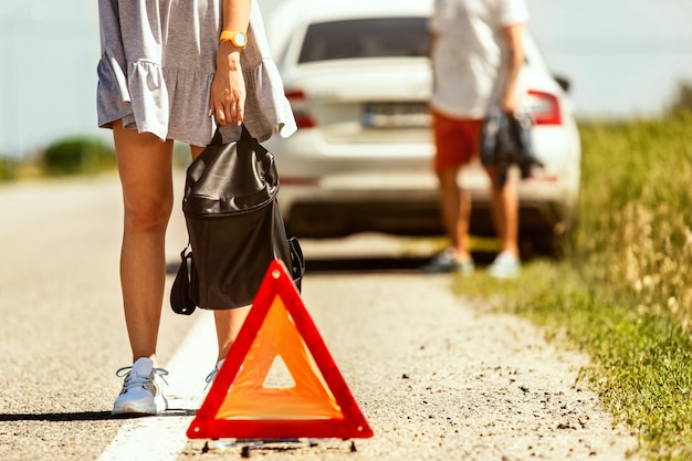 Bezpłatne zdjęcie młoda para zepsuła samochód w drodze na odpoczynek. próbują zatrzymać innych kierowców i poprosić o pomoc lub autostop