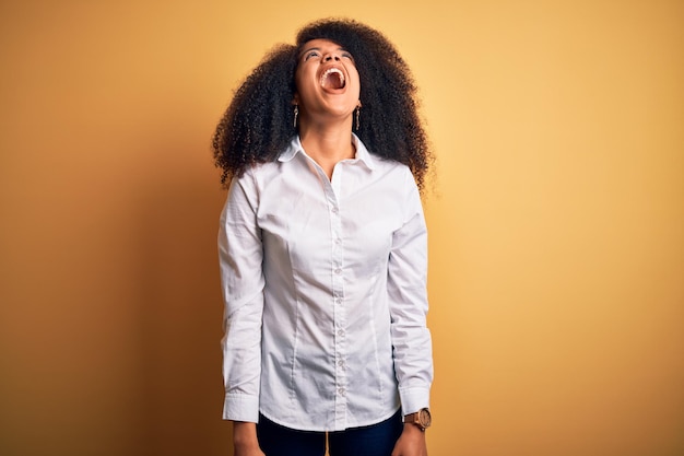 Bezpłatne zdjęcie młoda piękna afroamerykanka elegancka kobieta z włosami afro stojąca na żółtym tle wściekła i szalona krzycząca sfrustrowana i wściekła krzycząca ze złością wściekłość i agresywna koncepcja