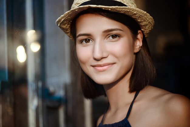 Młoda piękna brunetki dziewczyna w kapeluszowy ono uśmiecha się.