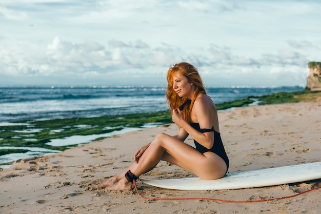 młoda piękna dziewczyna pozuje na plaży z desek surfingowych, kobieta surfer, fale oceanu