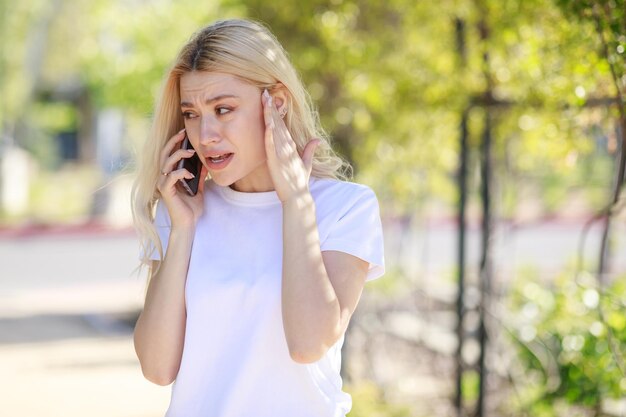 Młoda piękna dziewczyna rozmawia przez telefon i płacze