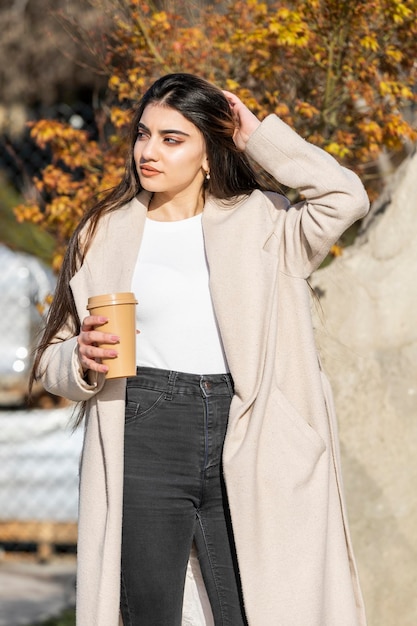 Młoda piękna dziewczyna trzyma filiżankę kawy i odwraca wzrok Odkryty piękno portret kobiety moda model ładna dziewczyna styl uliczny casual