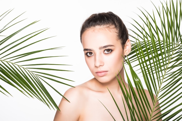 Młoda piękna kobieta pozuje z zielonymi palmowymi liśćmi