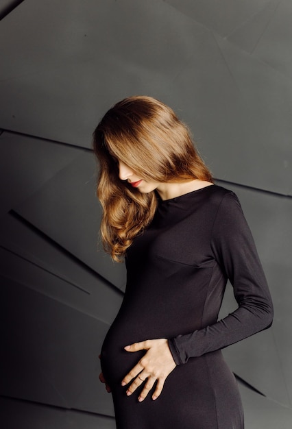 Młoda piękna kobieta w ciąży w czarnej sukni Koncepcja wyglądu mody ciążowej