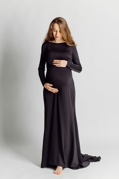 Młoda piękna kobieta w ciąży w czarnej sukni Koncepcja wyglądu mody ciążowej