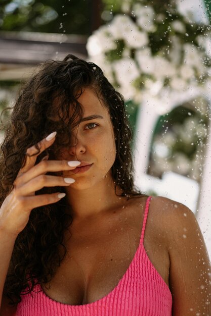 młoda piękna kobieta w stroju kąpielowym pod letnim prysznicem na plaży