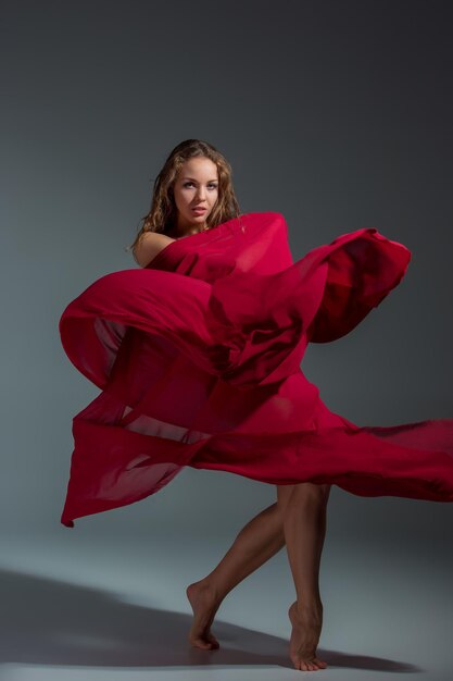 Młoda piękna tancerka w czerwonej sukience pozowanie na ciemnoszarym tle studio. Nowoczesna, Współczesna, improwizacja