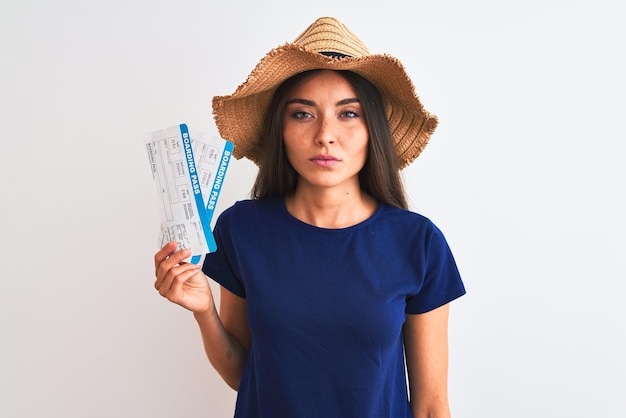 Bezpłatne zdjęcie młoda piękna turystka trzymająca bilet na kartę pokładową na odizolowanym białym tle z pewnym wyrazem twarzy na inteligentnej twarzy, myśląca poważnie