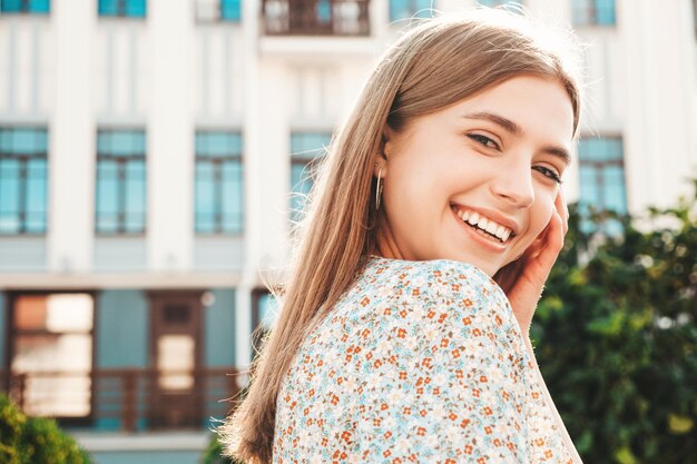 Młoda piękna uśmiechnięta kobieta hipster w modnej letniej sukience Seksowna beztroska kobieta pozuje na tle ulicy o zachodzie słońca Pozytywny model na zewnątrz Wesoły i szczęśliwy