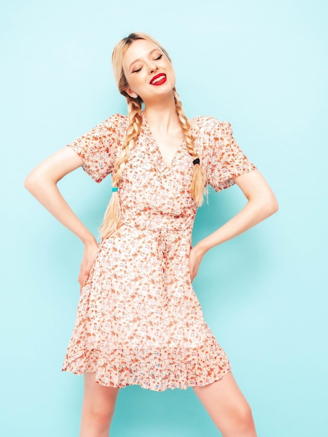 Młoda piękna uśmiechnięta kobieta w modnej letniej sukience Seksowna beztroska blond kobieta pozuje w pobliżu niebieskiej ściany w studio Model zabawy Wesoły i szczęśliwy