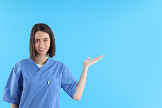 Młoda pielęgniarka praktykantka na niebieskim tle