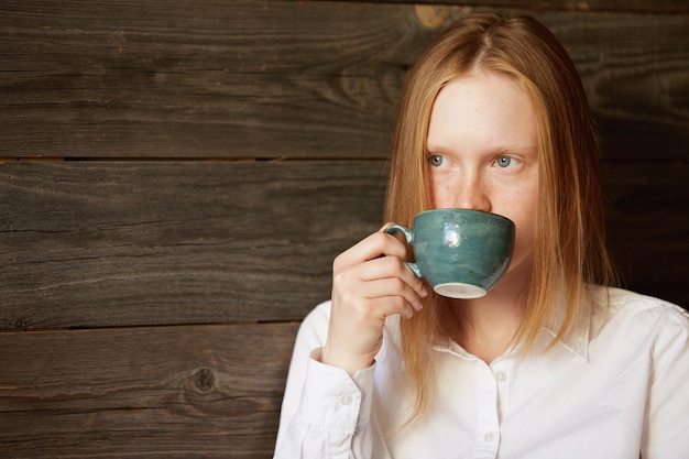 Bezpłatne zdjęcie młoda rudowłosa kobieta w kawiarni