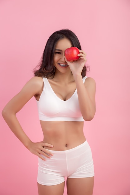 młoda sportowa kobieta trzyma świeże jabłko po sesji siłowej promującej zdrowe odżywianie i zdrowy styl życia