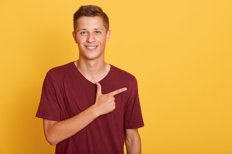 Bezpłatny plik Zdjęcie młoda studencka samiec wskazuje na boku z jego palcem wskazującym
