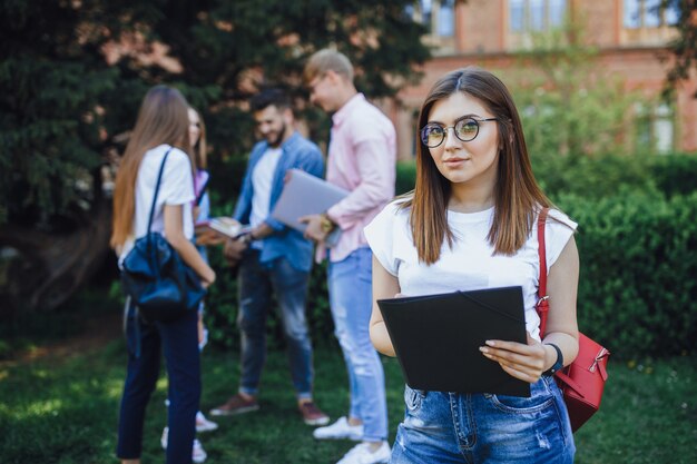 młoda studentka stojąca w kampusie i uśmiech.