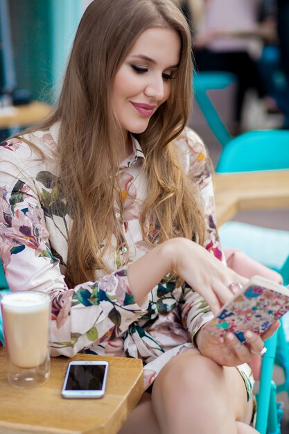 Młoda stylowa kobieta siedzi w kawiarni