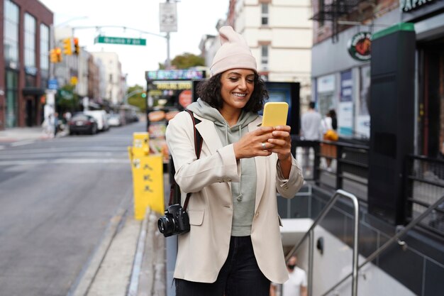 Młoda stylowa kobieta w mieście używająca smartfona do eksploracji