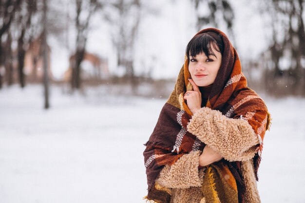 Młoda szczęśliwa kobieta w ciepłych płótnach w zima parku