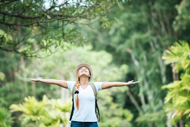 Młoda szczęśliwa kobieta z plecak podnoszący rękę cieszy się z naturą.