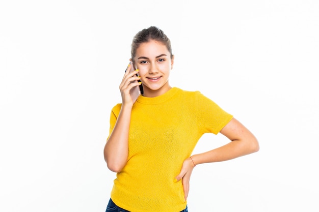 Młoda szczęśliwa nastoletnia dziewczyna dzwoni z telefonem komórkowym odizolowywającym na bielu