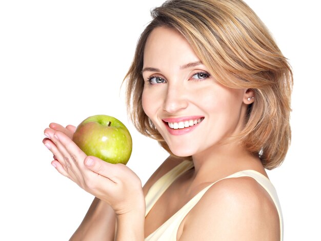 Młoda szczęśliwa uśmiechnięta kobieta z zielonym jabłkiem na białym tle.