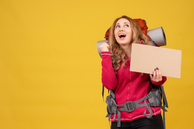Młoda uśmiechnięta podróżująca dziewczyna, zbierając swój bagaż, pokazując wolne miejsce na pisanie i wyszukiwanie