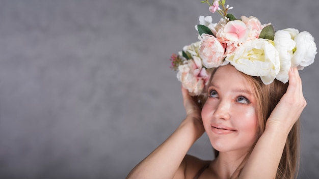 Bezpłatne zdjęcie młoda uśmiechnięta romantyczna dama trzyma pięknego kwiatu wianek