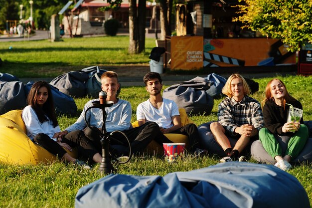 Młoda wieloetniczna grupa ludzi oglądająca film w puf w kinie na świeżym powietrzu