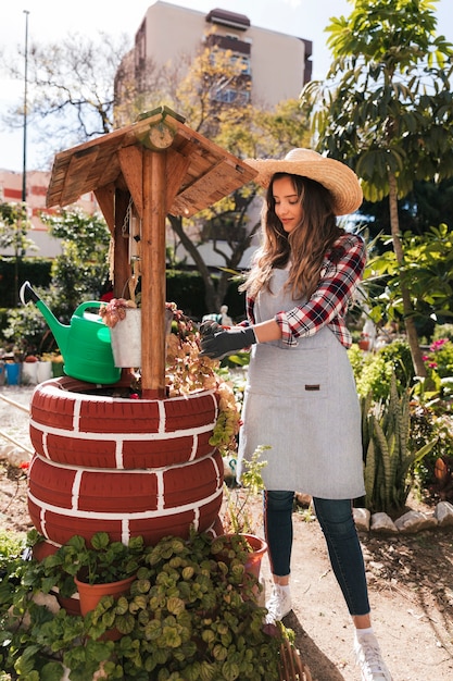 Młoda żeńska ogrodniczka dba o rośliny nad handmade studnią