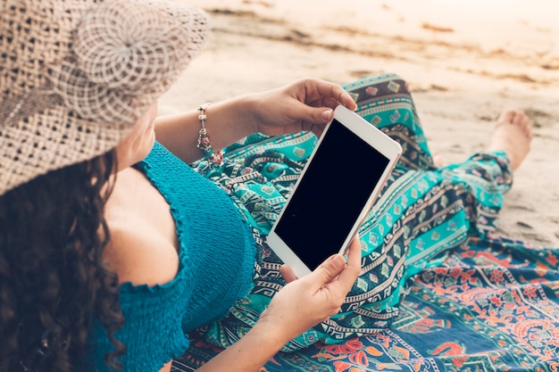 Bezpłatne zdjęcie młoda żeńska używa pastylka na plaży