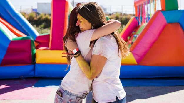 Młode kobiety obejmując się nawzajem świętując festiwal holi