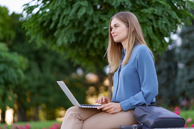 Młode kobiety pracują na laptopie na placu miasta