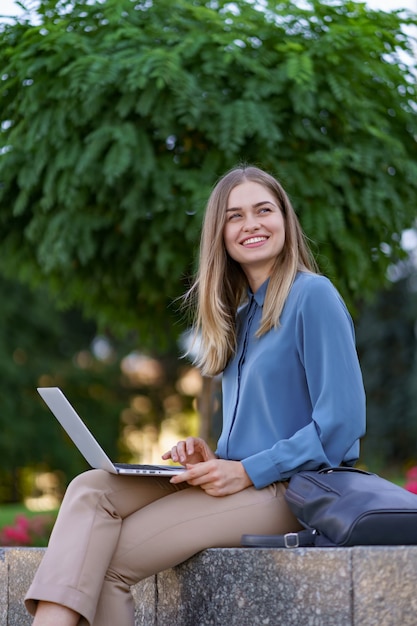 Młode kobiety pracują na laptopie na placu miasta