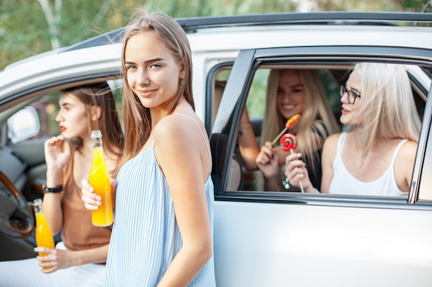 Młode kobiety w samochodzie uśmiechają się i piją sok