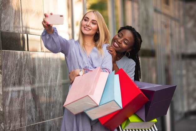 Młode kobiety z torba na zakupy bierze selfie