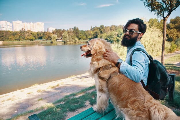 Młodego człowieka obsiadanie z jego psem na krześle w parku
