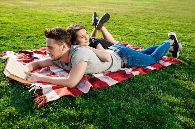 Młodej pięknej pary uśmiechnięty czytanie przy parkiem.