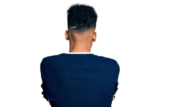 Bezpłatne zdjęcie młody afroamerykanin ubrany w zwykłe ubrania, stojący tyłem, odwracający wzrok ze skrzyżowanymi ramionami