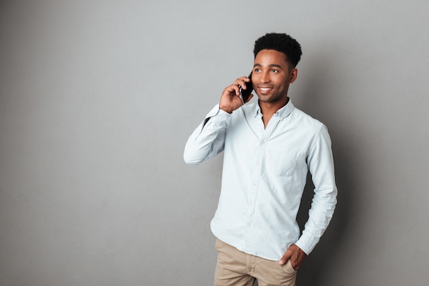 młody afrykański mężczyzna rozmawia przez telefon komórkowy stojąc