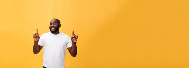 Młody amerykanina afrykańskiego pochodzenia mężczyzna wskazuje upwards nad żółtym tłem