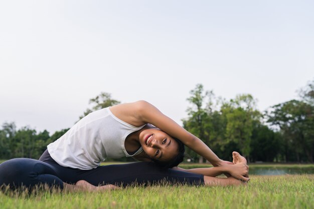 Młody azjatykci kobiety joga outdoors utrzymuje spokój i medytuje podczas gdy ćwiczyć joga