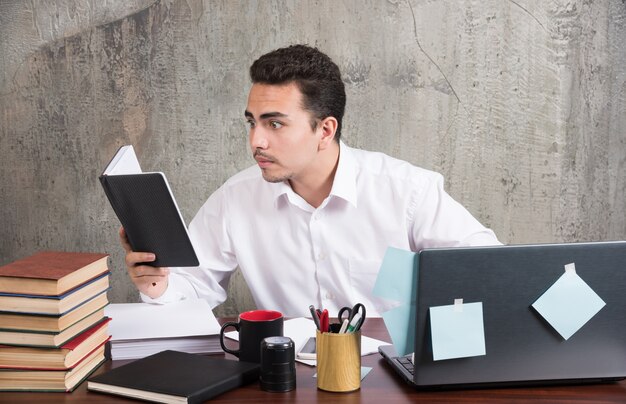 Młody biznesmen przyglądając się uważnie notebooka przy biurku.