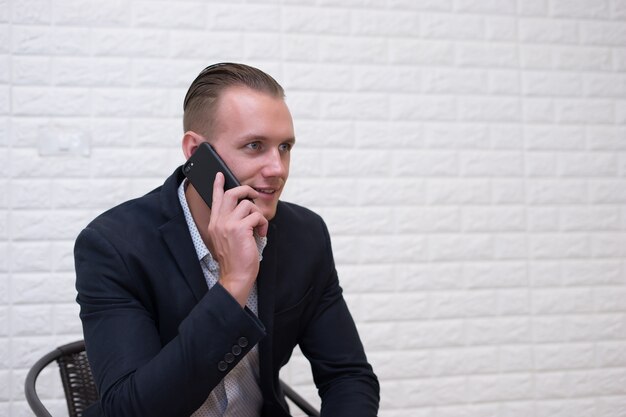 Młody biznesmena obsiadanie opowiada na telefonie przy biurem