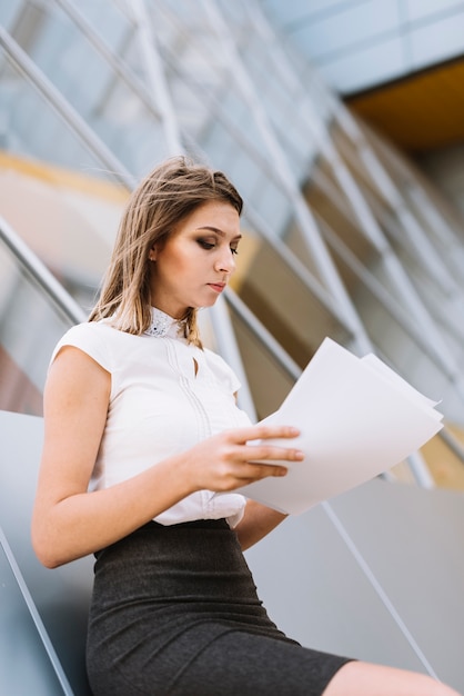 Bezpłatne zdjęcie młody bizneswoman w formalwear czytelniczych dokumentach