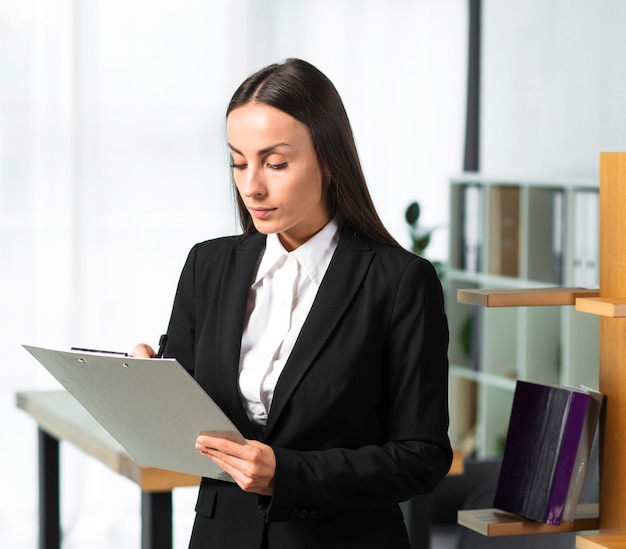 Młody bizneswomanu writing na schowku z piórem