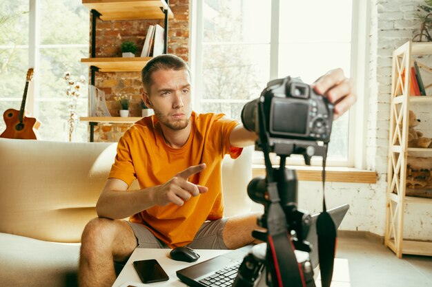 Młody bloger kaukaski z profesjonalnym aparatem nagrywającym wideo przegląd gadżetów w domu