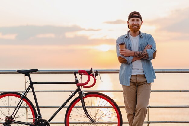 Młody brodaty mężczyzna podróżujący na rowerze na morzu słońca