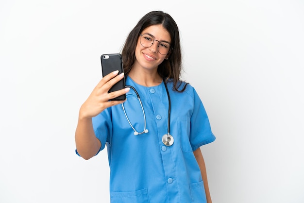 Młody chirurg lekarz kaukaski kobieta na białym tle robi selfie